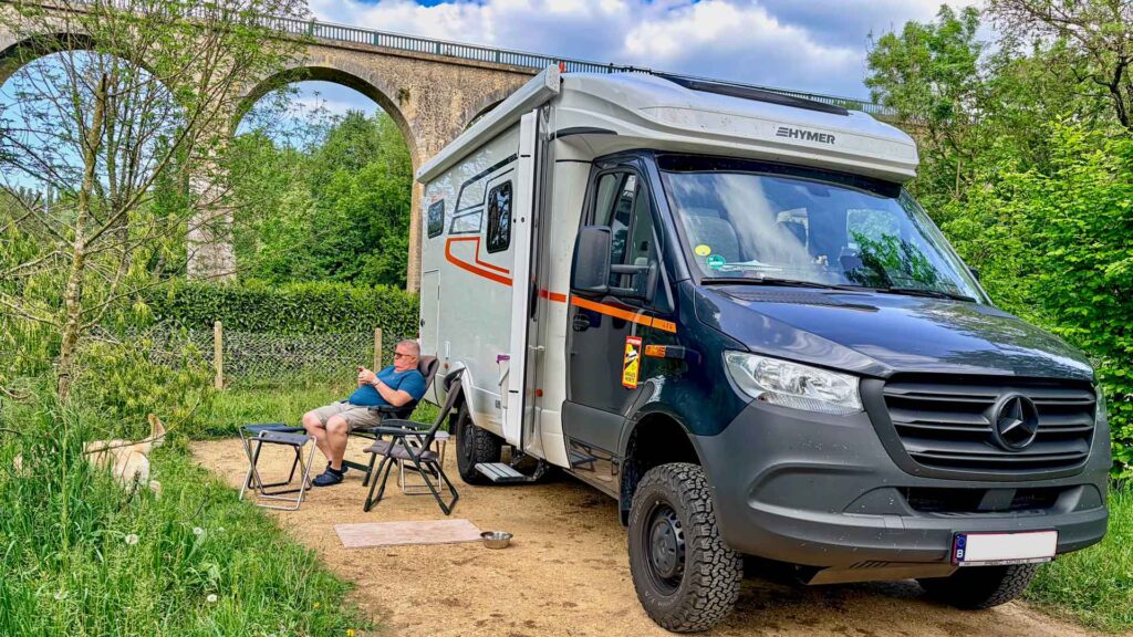Robert zittend naast de Hymer ML-T 570 met op de achtergrond de brug bij Saint-Benoît-sur-Loire tijdens de Marokko camperreis 2026